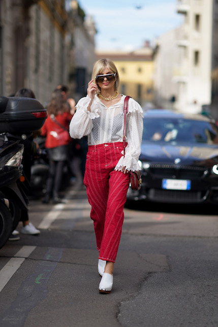 ragazza con zoccoli, pantaloni rossi e camicia bianca