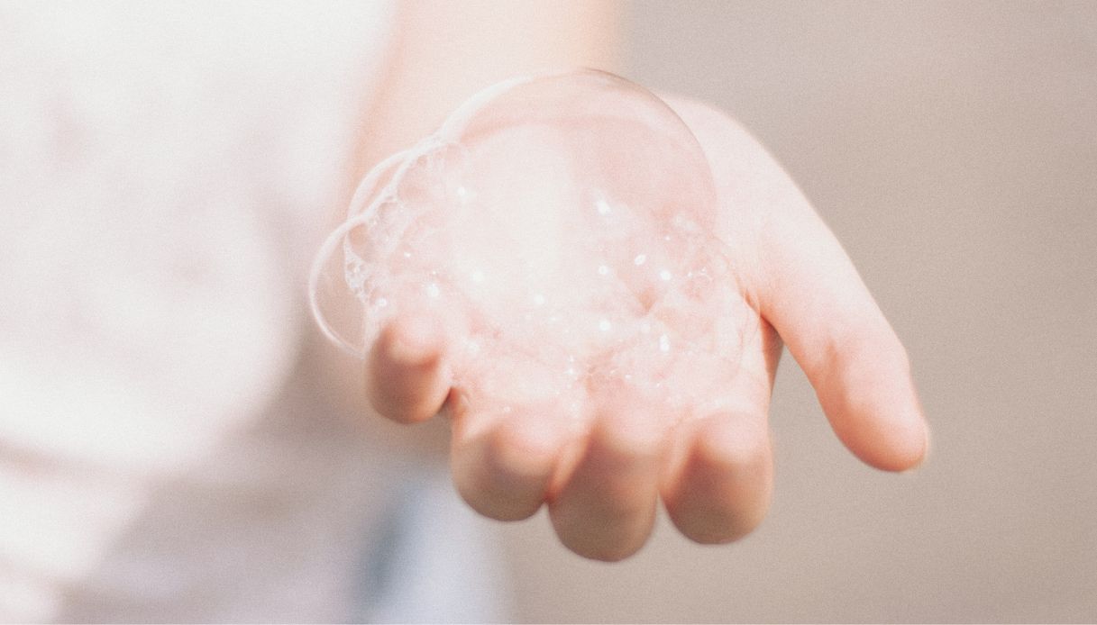 mano con palmo verso l'alto e sopra bolle di sapone