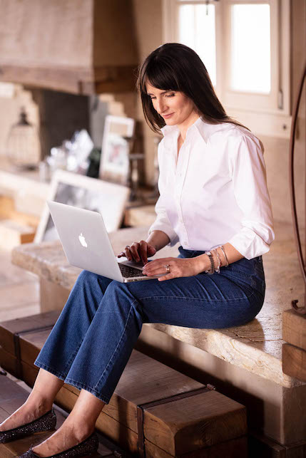 Ragazza con jeans e camicia bianca che lavora al computer