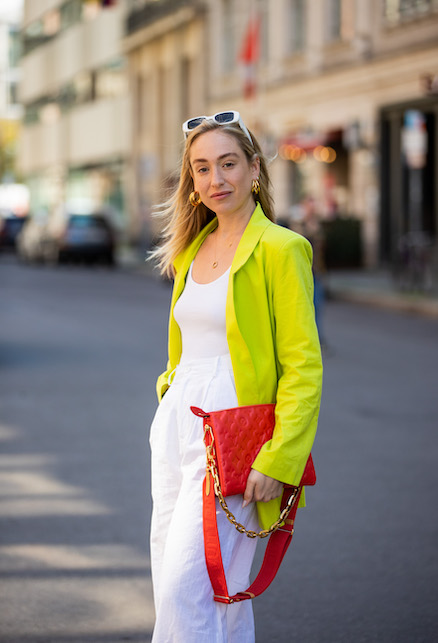 modella con giacca gialla, body e pantaloni bianchi e borsa rossa