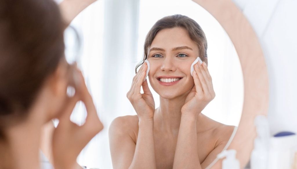 Donna allo specchio applica maschera viso
