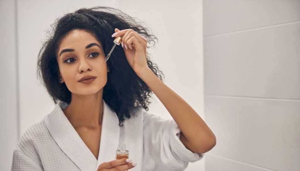 Donna riccia mulatta applica siero viso