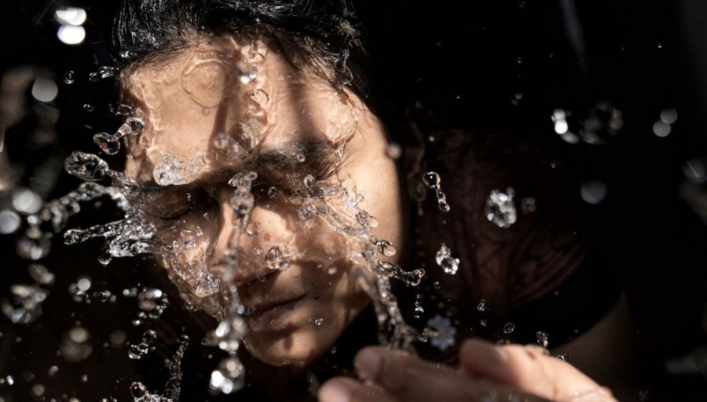 ragazza lava il viso splash acqua
