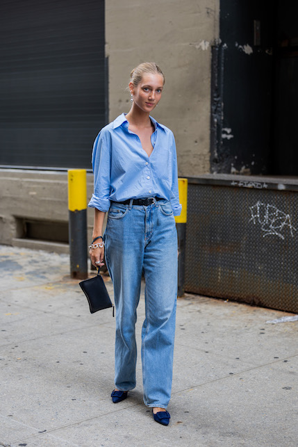 Ragazza con camicia boyfriend, camicia azzurra e pochette a mano