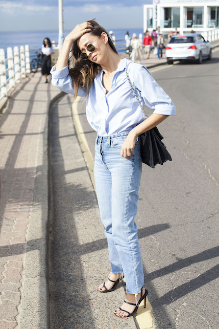 ragazza con jeans, camicia azzurra, borsa e sandali neri