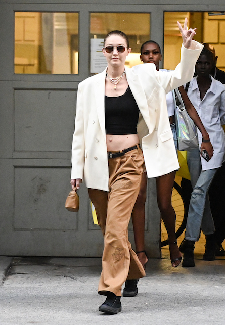 Gigi Hadid con crop top nero, blazer bianco e pantaloni maroni