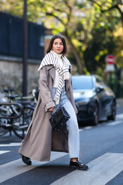 ragazza con trench, jeans e pullover a righe