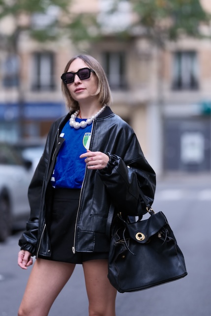 ragazza con t-shirt blu, giacca di pelle e collana di perle