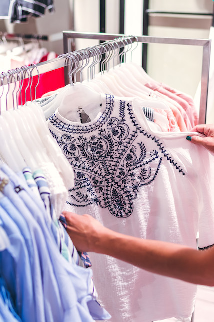 ragazza che guarda vestiti appesi in negozio