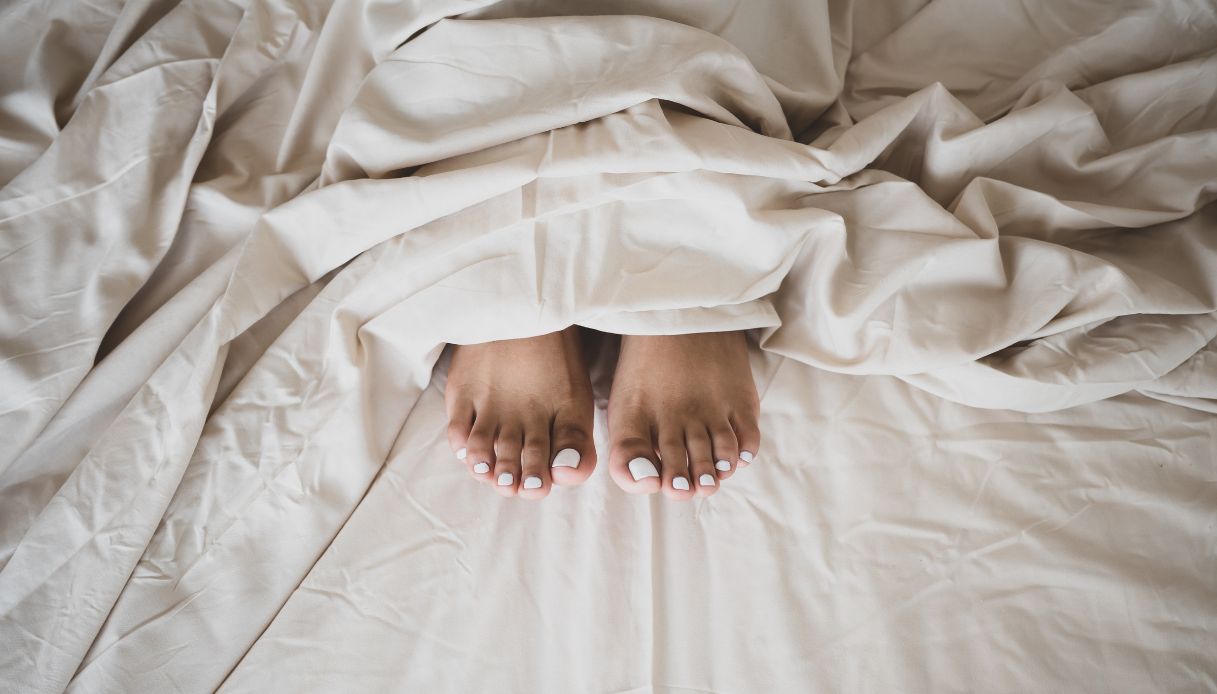 piedi con smalto bianco che escono da coperte