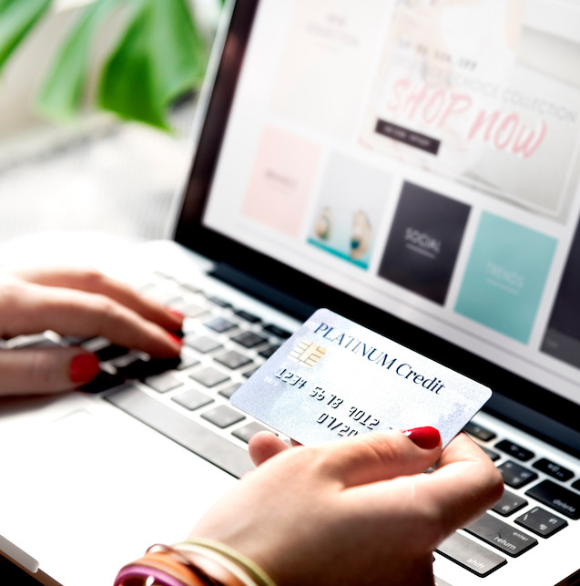 ragazza che tiene una carta di credito davanti ad un computer 