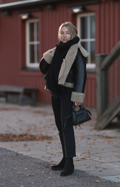 ragazza con giacca in shearling nera e pantaloni neri