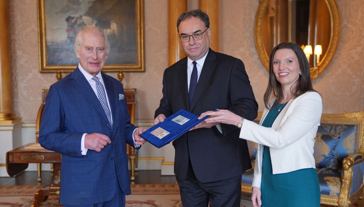 Re Carlo mentre riceve le prime banconote con il suo volto dal governatore della Banca d'Inghilterra e da Sarah John, capo cassiera della Banca